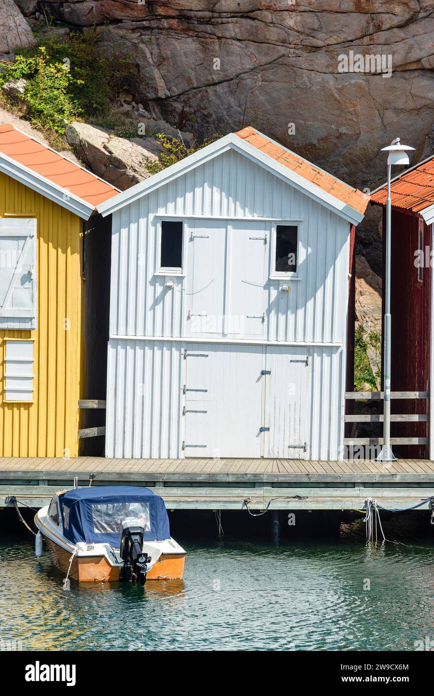 Magazzino con facciata in legno bianco di fronte a rocce di granito sul lungomare del porto di Smögen, nell'arcipelago della costa occidentale svedese Foto Stock