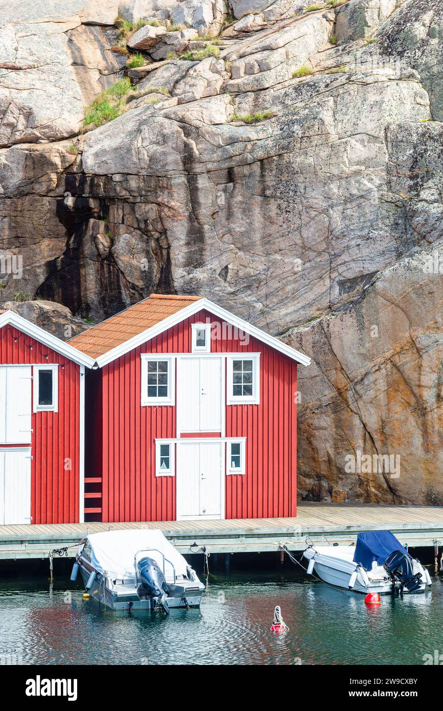 Magazzino con facciata in legno rosso davanti a rocce di granito sul lungomare del porto di Smögen, nell'arcipelago della costa occidentale svedese Foto Stock