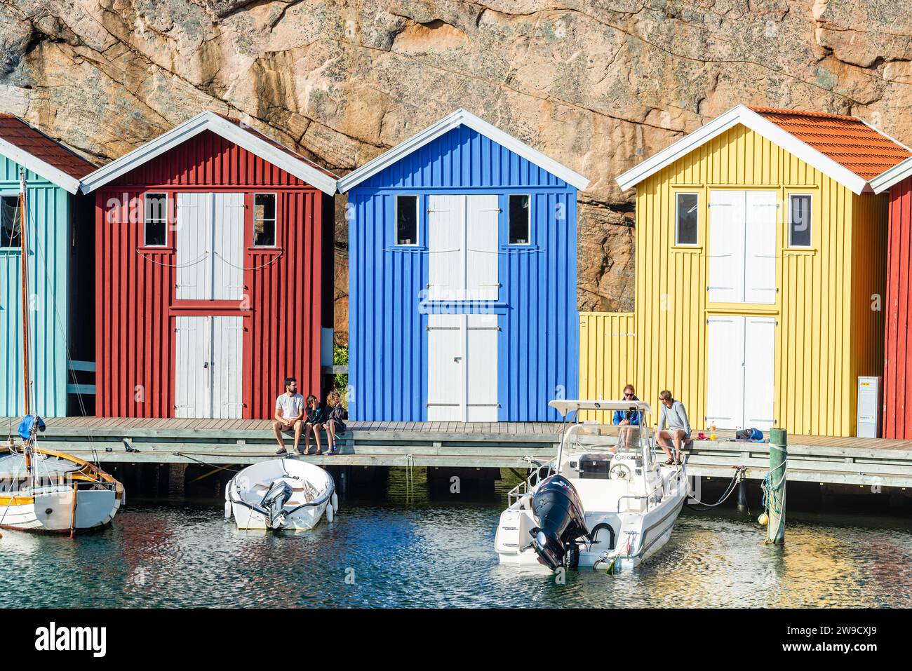 Capannoni per barche e magazzini con colorate facciate in legno e rocce di granito nel porto di Smögen, nell'arcipelago della costa occidentale svedese Foto Stock