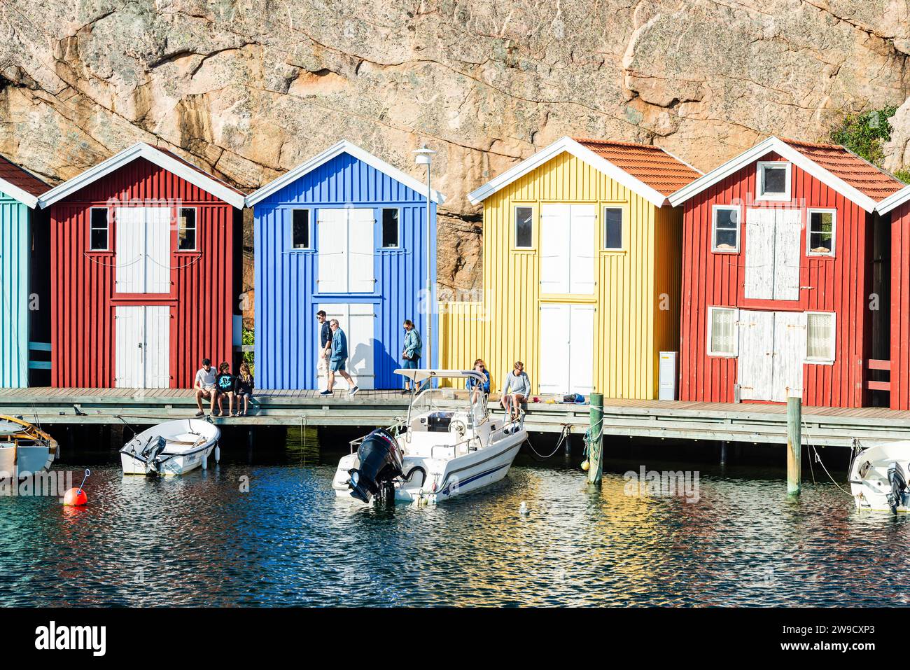 Capannoni per barche e magazzini con colorate facciate in legno e rocce di granito nel porto di Smögen, nell'arcipelago della costa occidentale svedese Foto Stock