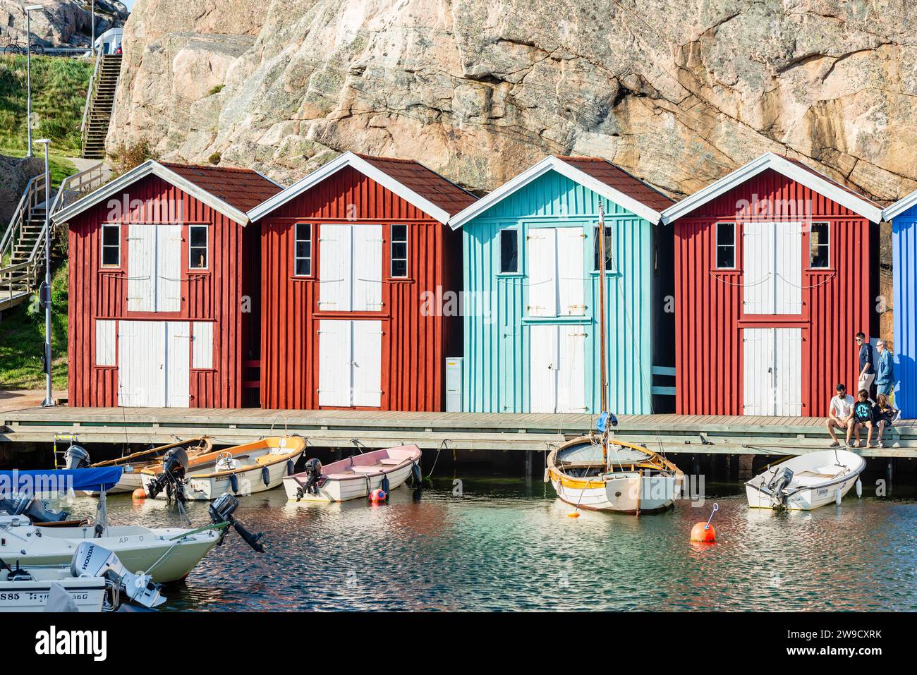 Capannoni per barche e magazzini con colorate facciate in legno e rocce di granito nel porto di Smögen, nell'arcipelago della costa occidentale svedese Foto Stock