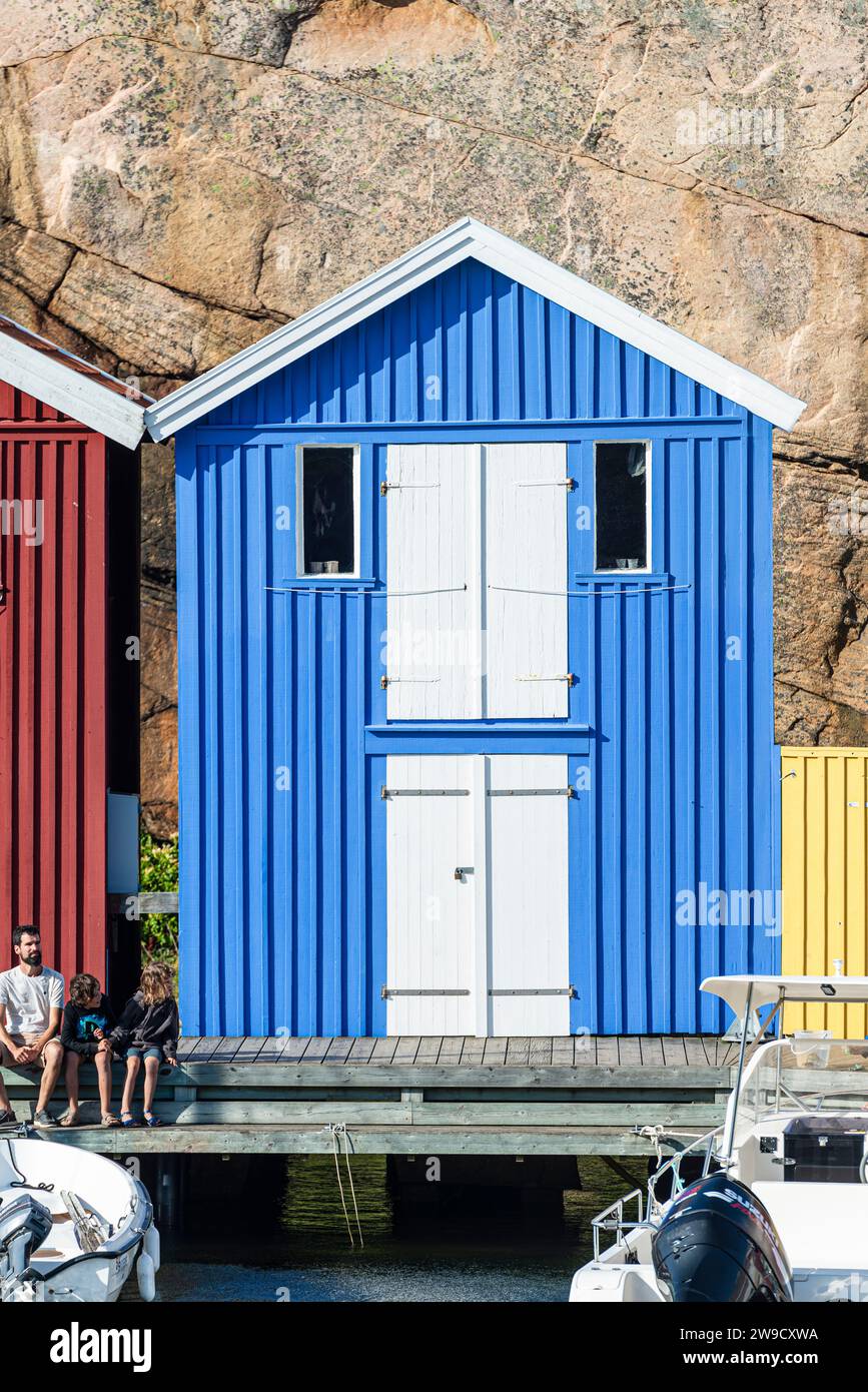 Magazzino con facciata in legno blu davanti a rocce di granito sul lungomare del porto di Smögen, nell'arcipelago della costa occidentale svedese Foto Stock