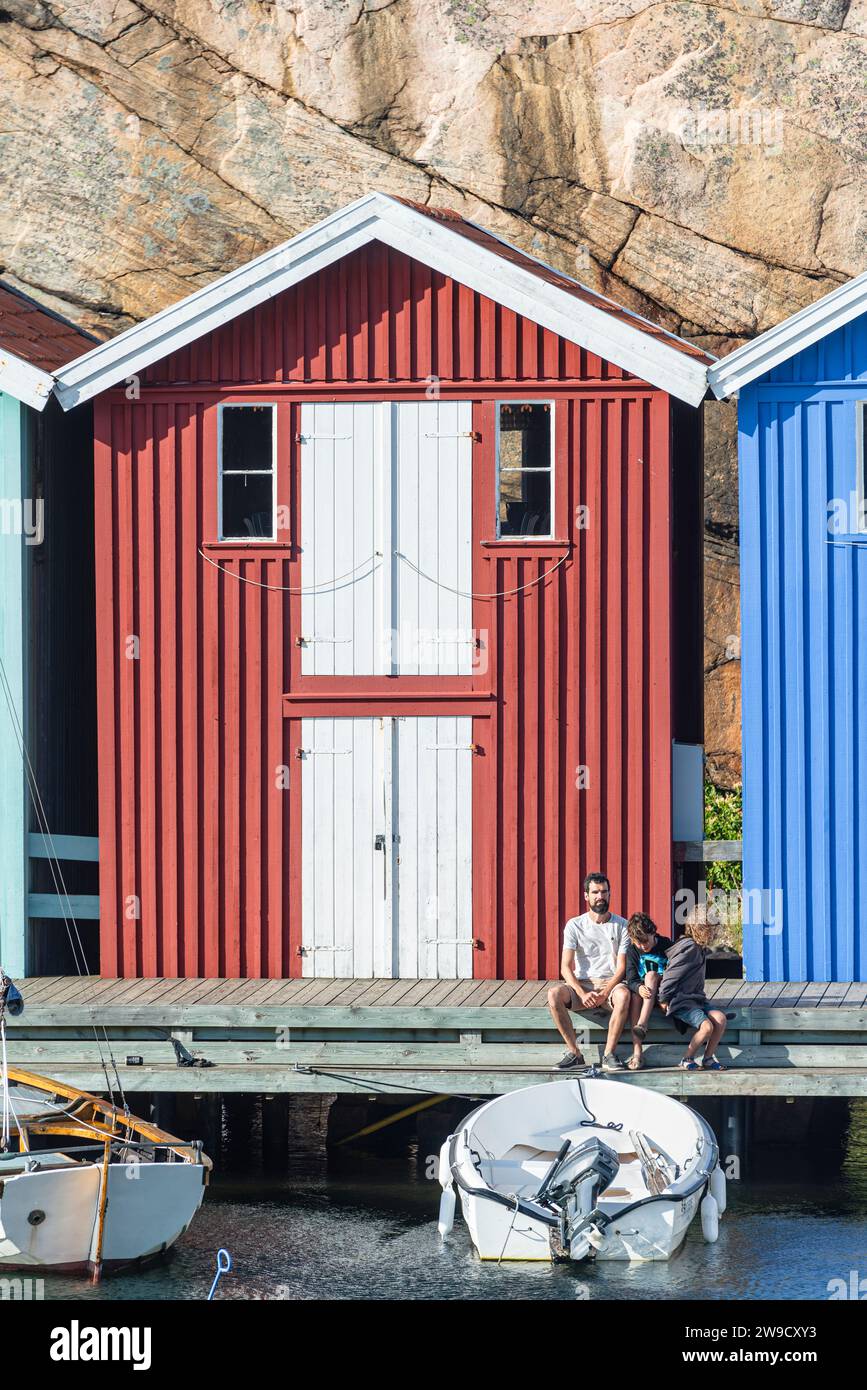 Magazzino con facciata in legno rosso davanti a rocce di granito sul lungomare del porto di Smögen, nell'arcipelago della costa occidentale svedese Foto Stock
