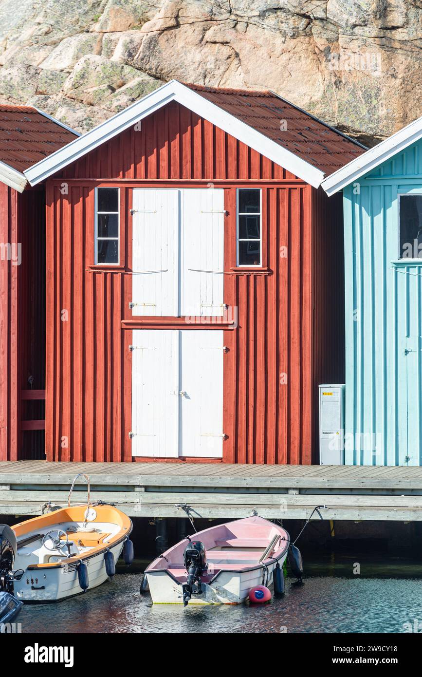 Magazzino con facciata in legno rosso davanti a rocce di granito sul lungomare del porto di Smögen, nell'arcipelago della costa occidentale svedese Foto Stock