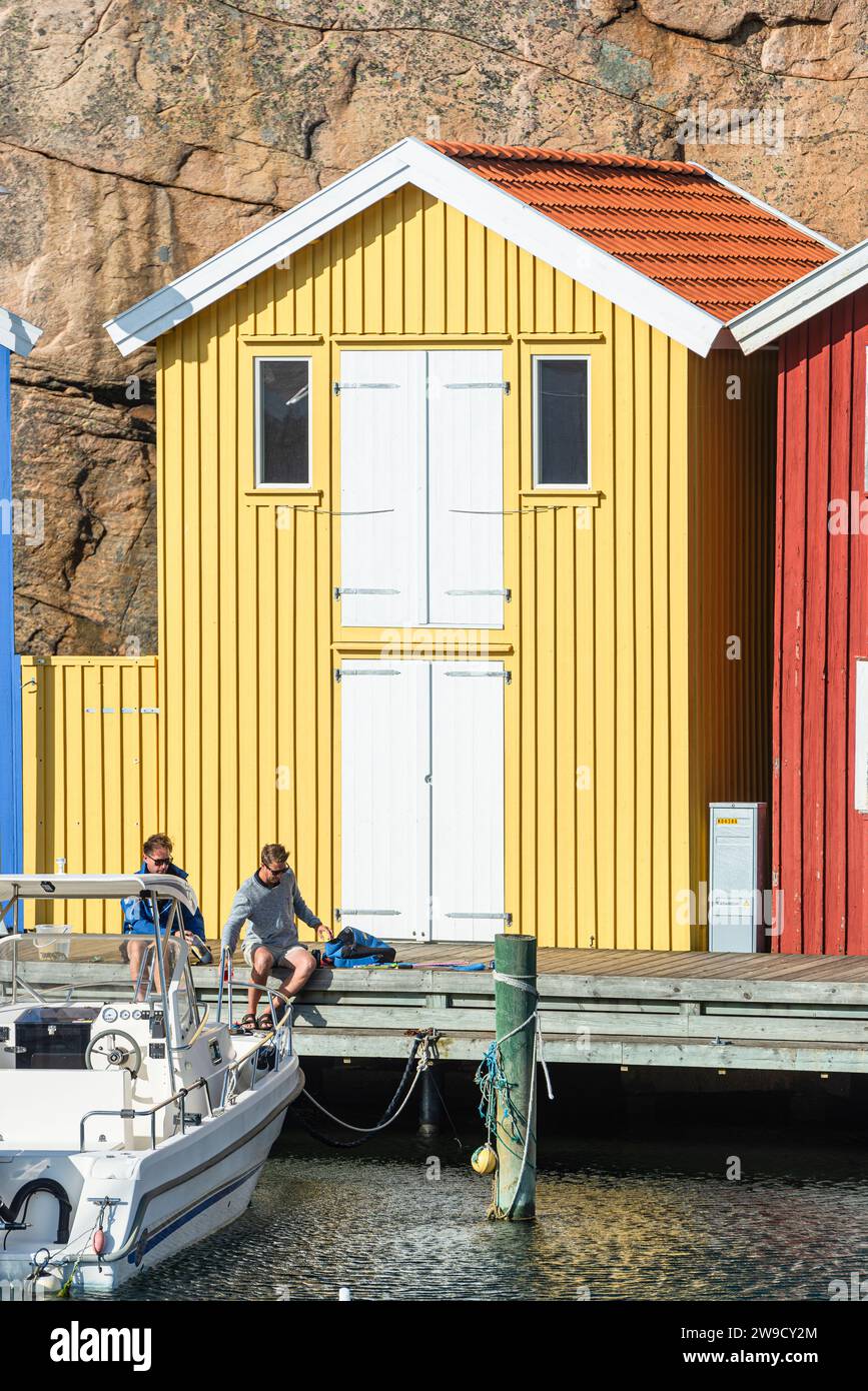 Magazzino con facciata in legno giallo davanti a rocce di granito sul lungomare del porto di Smögen, nell'arcipelago della costa occidentale svedese Foto Stock