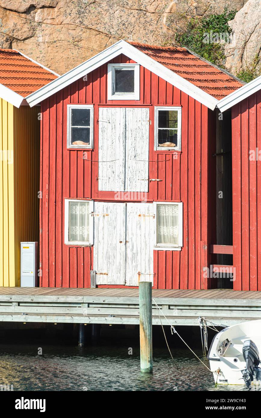 Magazzino con facciata in legno rosso davanti a rocce di granito sul lungomare del porto di Smögen, nell'arcipelago della costa occidentale svedese Foto Stock