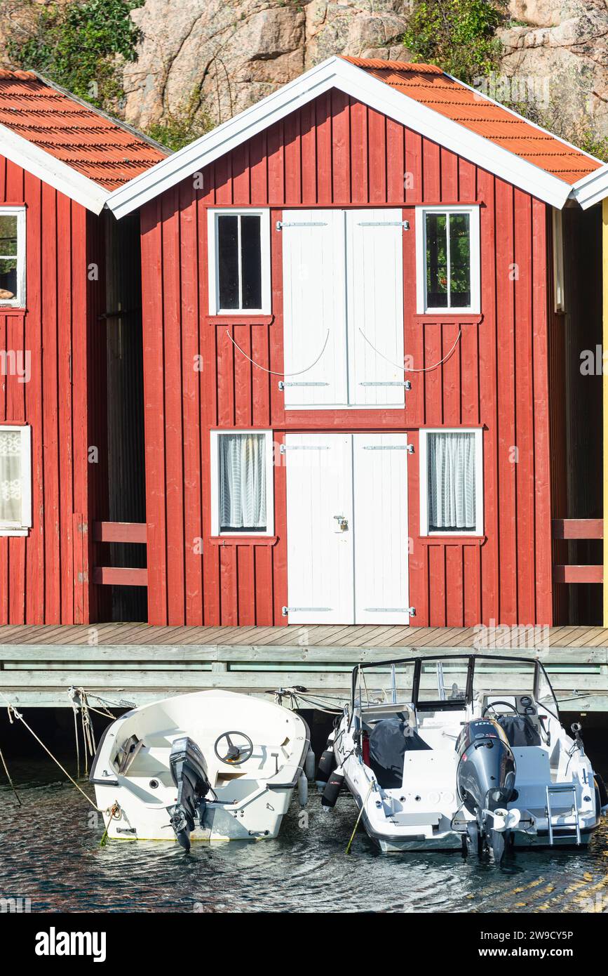Magazzino con facciata in legno rosso davanti a rocce di granito sul lungomare del porto di Smögen, nell'arcipelago della costa occidentale svedese Foto Stock