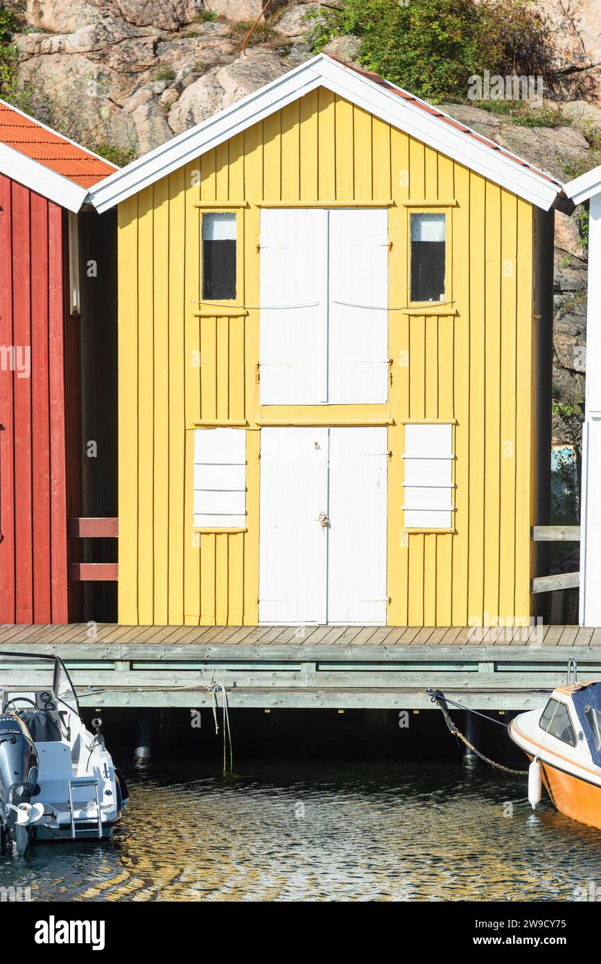 Magazzino con facciata in legno giallo davanti a rocce di granito sul lungomare del porto di Smögen, nell'arcipelago della costa occidentale svedese Foto Stock