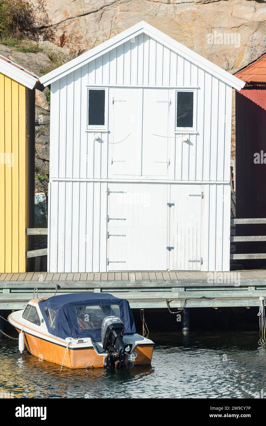 Magazzino con facciata in legno bianco di fronte a rocce di granito sul lungomare del porto di Smögen, nell'arcipelago della costa occidentale svedese Foto Stock