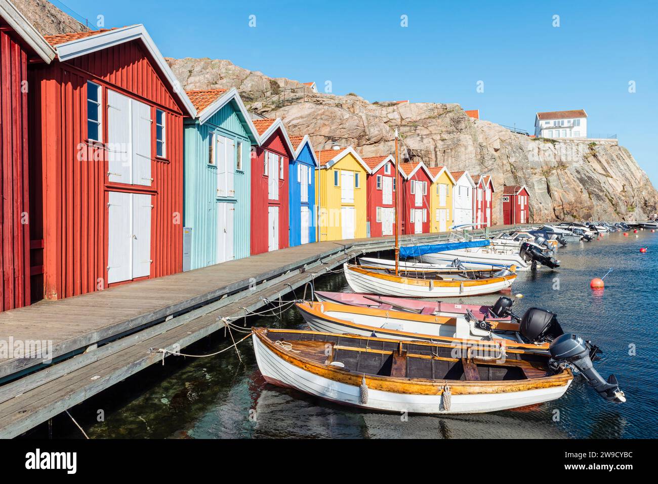 Capannoni per barche e magazzini con facciate in legno rosso tra rocce di granito nel porto di Smögen, nell'arcipelago della costa occidentale svedese Foto Stock