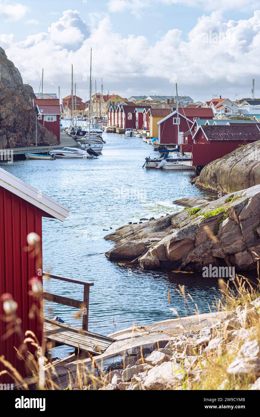 Capannoni per barche e magazzini con facciate in legno rosso e rocce di granito nel porto di Smögen, nell'arcipelago della costa occidentale svedese Foto Stock