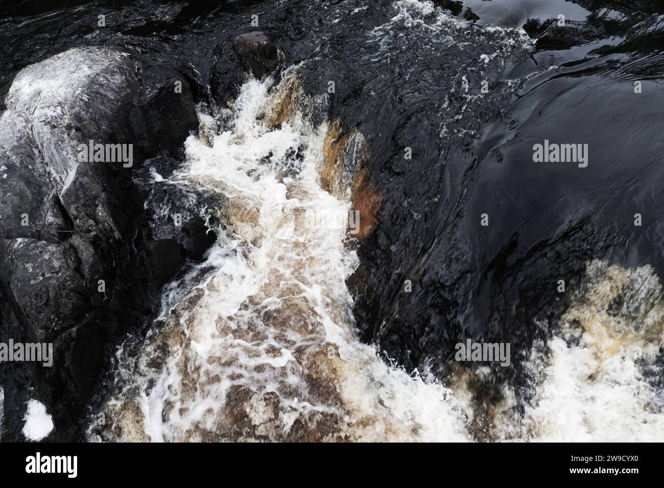 L'acqua veloce con schiuma passa sulle rocce nere. Cascate di Ruskeala, Repubblica di Carelia, Russia Foto Stock