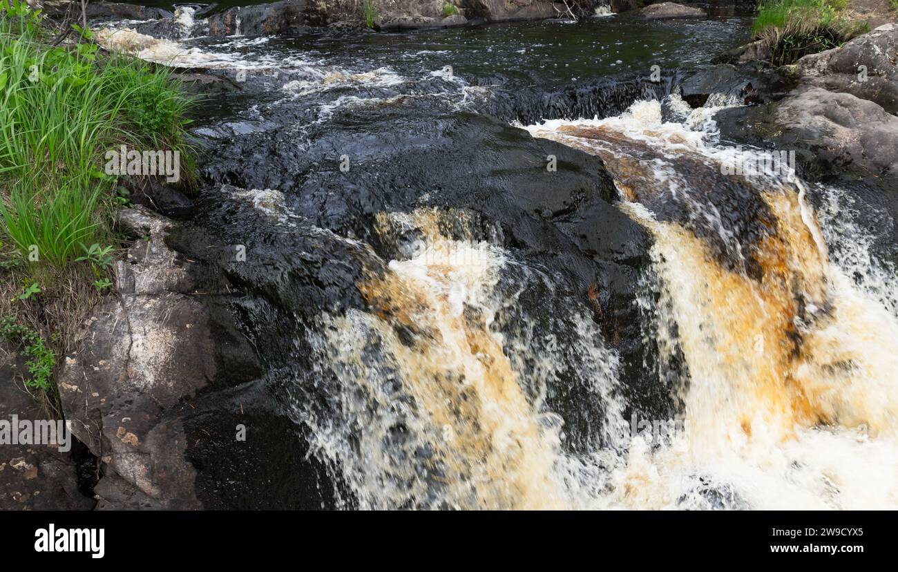 L'acqua scorre velocemente sulle rocce nere in una foresta. Cascate di Ruskeala, Repubblica di Carelia, Russia Foto Stock