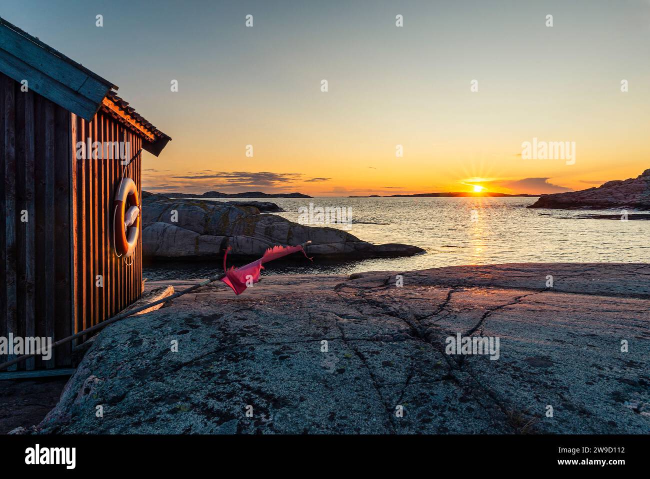 Capanna di legno al tramonto splendente sulle rocce nella riserva naturale Tjurpannan nell'arcipelago della costa occidentale svedese Foto Stock