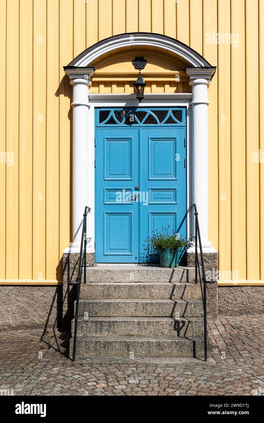Portale d'ingresso con porta blu su una casa di legno gialla nel centro di Fjällbacka sulla costa occidentale svedese sotto il sole Foto Stock
