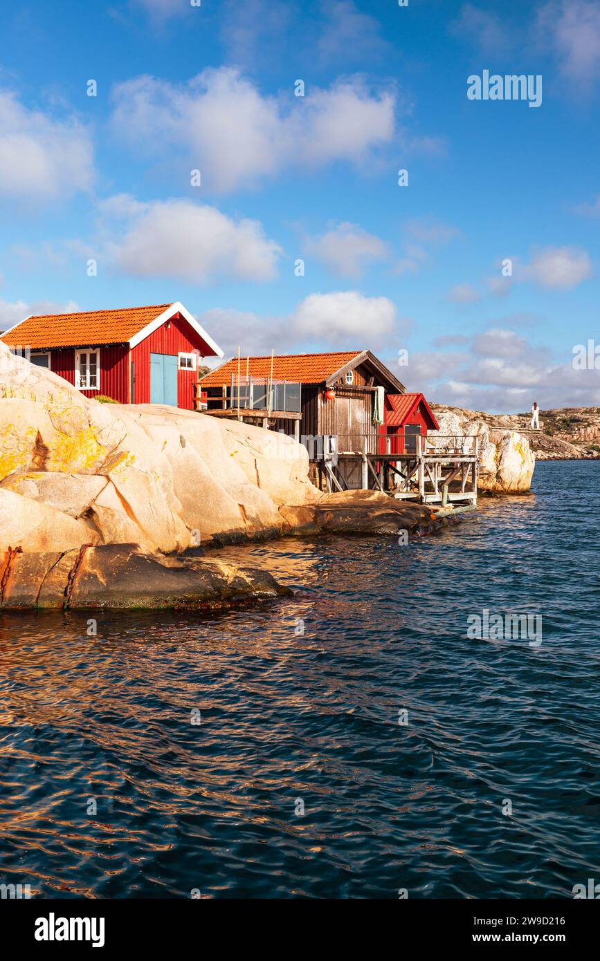 Le rocce di granito con le boathouses rosse nell'arcipelago della costa occidentale svedese brillano d'oro al tramonto Foto Stock