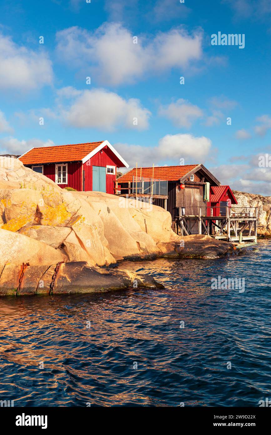 Le rocce di granito con le boathouses rosse nell'arcipelago della costa occidentale svedese brillano d'oro al tramonto Foto Stock