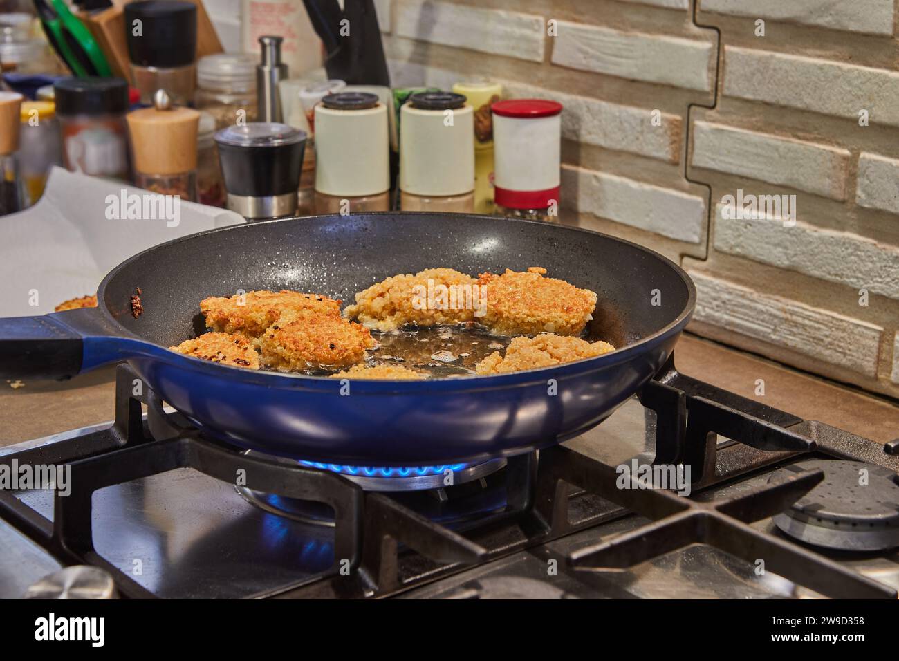 Cotolette di cigno preparate al momento frizzanti con olio caldo in una tipica cucina casalinga. Le cotolette dorate vengono fritte alla perfezione, creando una bocca- Foto Stock