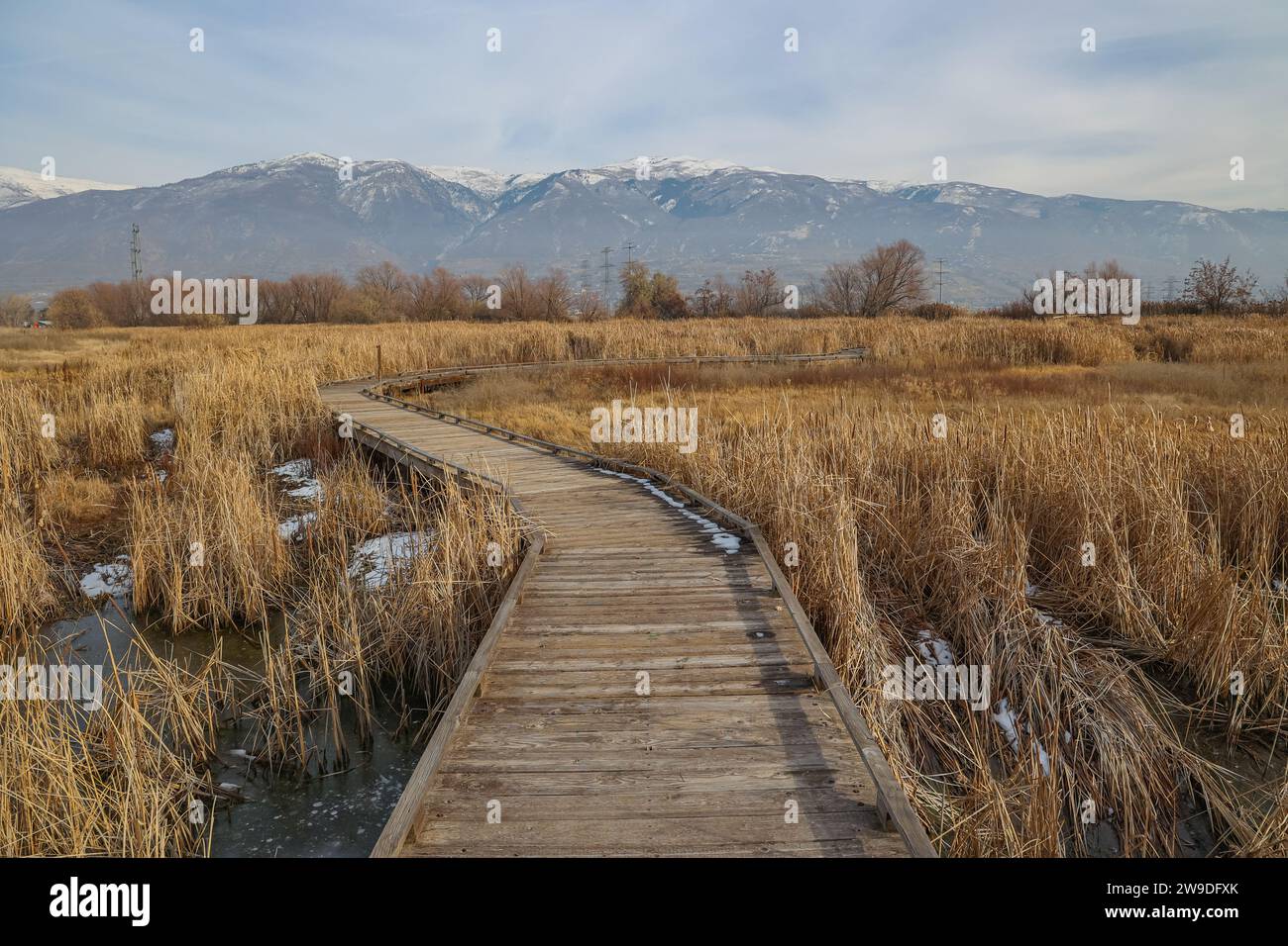 Una passerella lungo il sentiero naturalistico di Farmington Bay con la catena montuosa Wasatch sullo sfondo Foto Stock