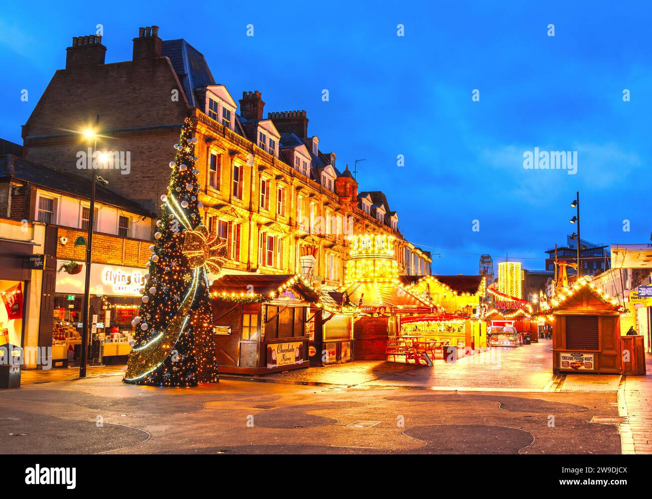 Bromley, Greater London, Inghilterra - 27 dicembre 2023: Il mercatino natalizio di Bromley brilla all'alba, adornato da tonalità calde. Il cielo blu incornicia le luci delle feste Foto Stock