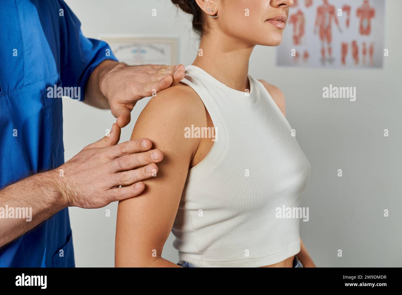 vista ritagliata del medico che controlla i muscoli della sua giovane paziente femminile durante l'appuntamento, assistenza sanitaria Foto Stock