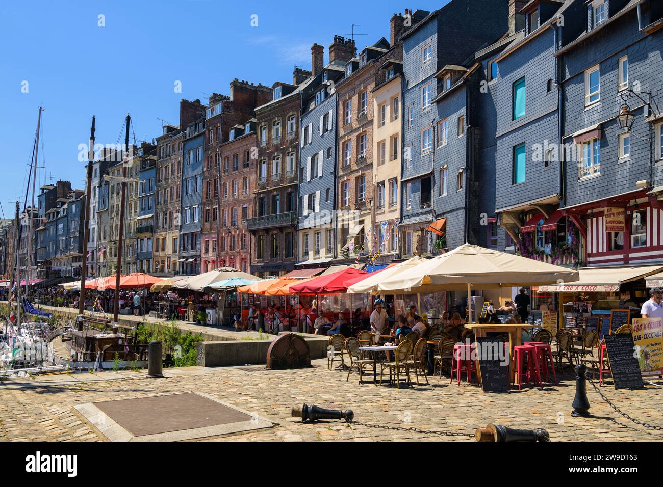 Honfleur, Francia - 24 luglio 2022: Case e ristoranti nel vecchio porto di Honfleur in una giornata di sole in estate, cielo blu Foto Stock