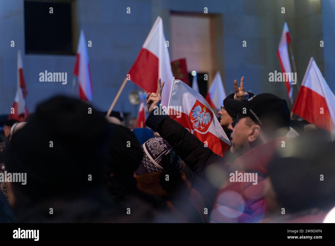 Il 26 dicembre 2023, la gente sventola le bandiere della Polonia al di fuori dello studio televisivo statale TVP di Varsavia, Polonia. Le persone si sono riunite al di fuori dello studio statale TVP nella protesta in corso contro la mossa della coalizione pro-europea appena eletta per reimporre l'integrità e l'obiettività nei media pubblici. Varsavia Polonia dimostrazione in difesa di TVP. 2023/12/26 Copyright: XMarekxAntonixIwanczukx MAI08447-Enhanced-NR Foto Stock