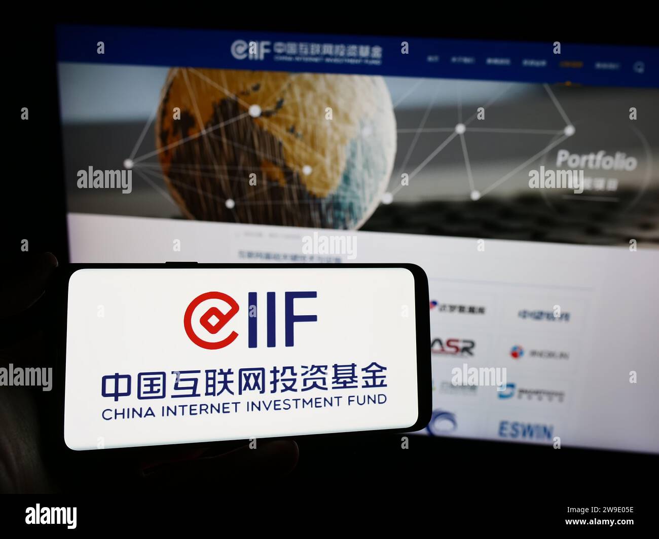 Persona che possiede uno smartphone con il logo del China Internet Investment Fund (CIIF) davanti al sito Web. Concentrarsi sul display del telefono. Foto Stock