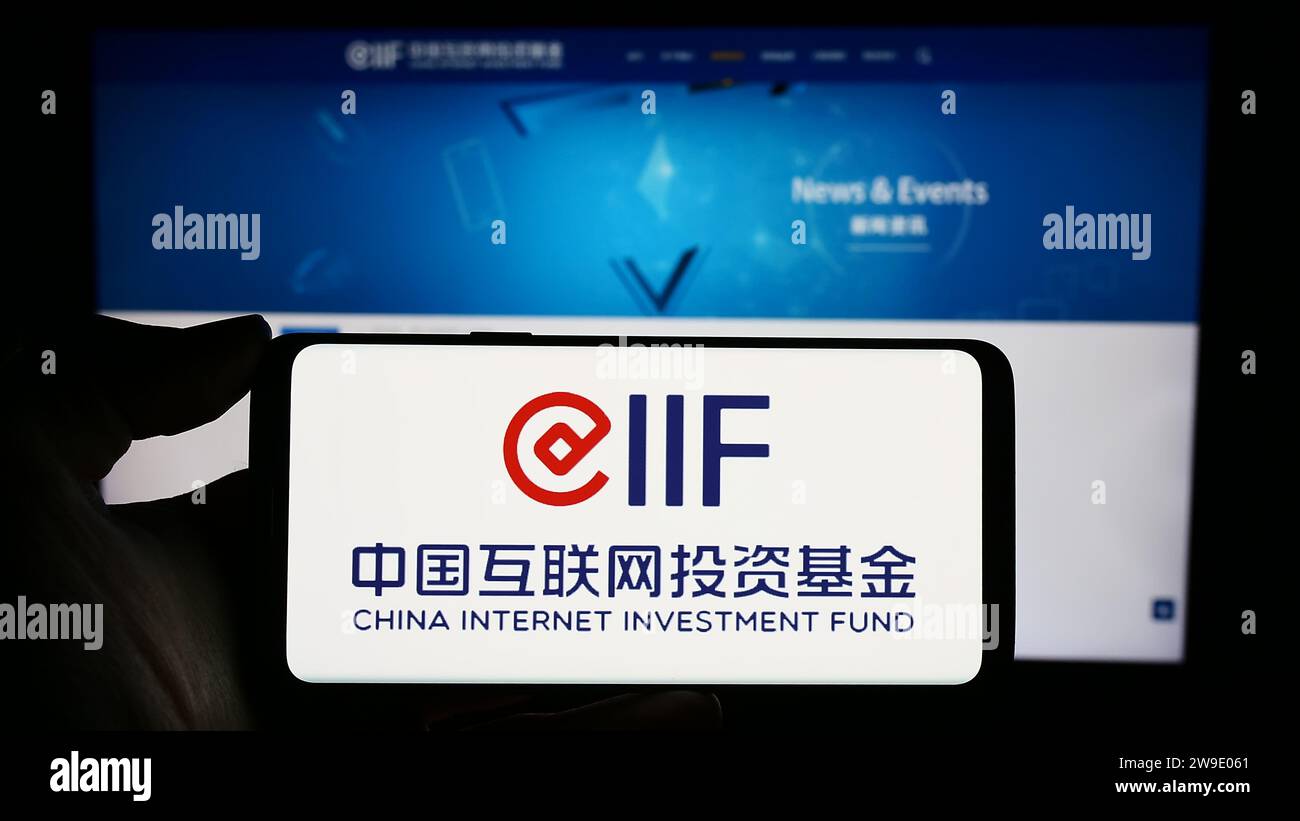 Persona in possesso di un cellulare con il logo del China Internet Investment Fund (CIIF) davanti alla pagina Web aziendale. Concentrarsi sul display del telefono. Foto Stock