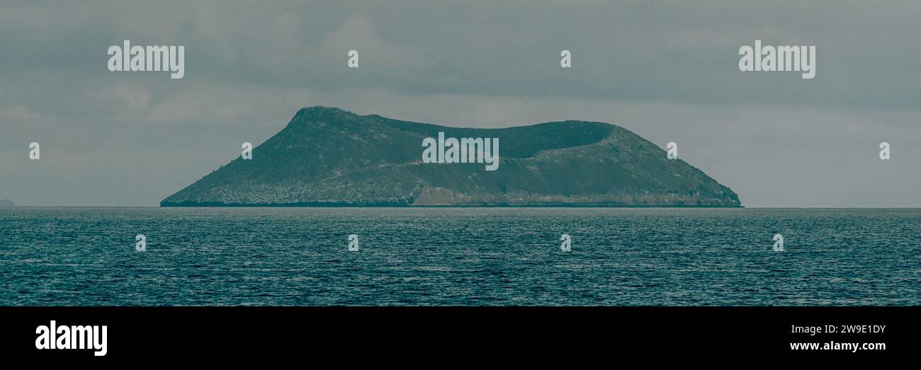 Isola isolata nelle Galapagos, Ecuador, circondata dalle limpide acque blu dell'Oceano Pacifico sotto un cielo nuvoloso. Foto Stock