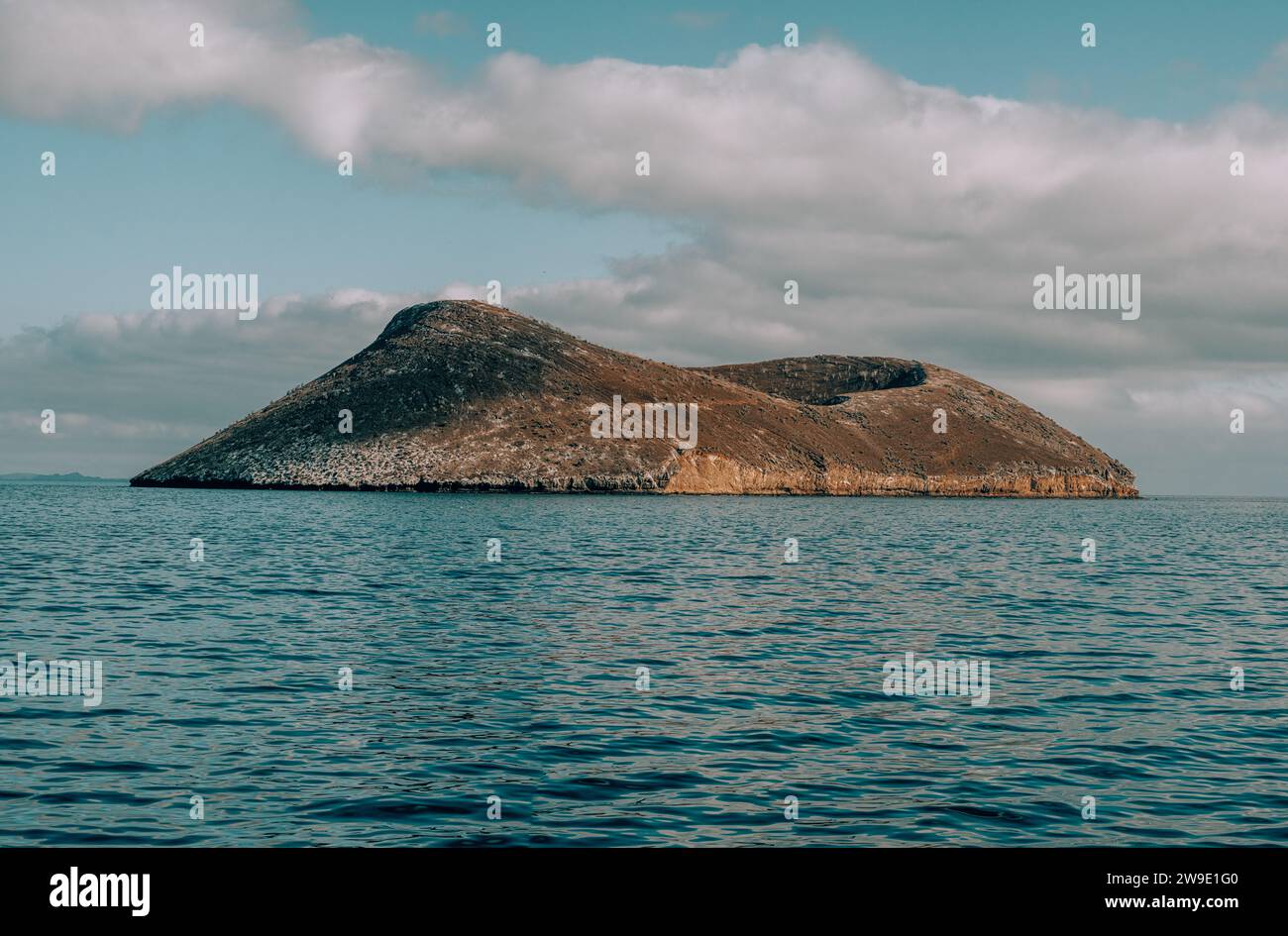 Isola isolata nelle Galapagos, Ecuador, circondata dalle limpide acque blu dell'Oceano Pacifico sotto un cielo nuvoloso. Foto Stock