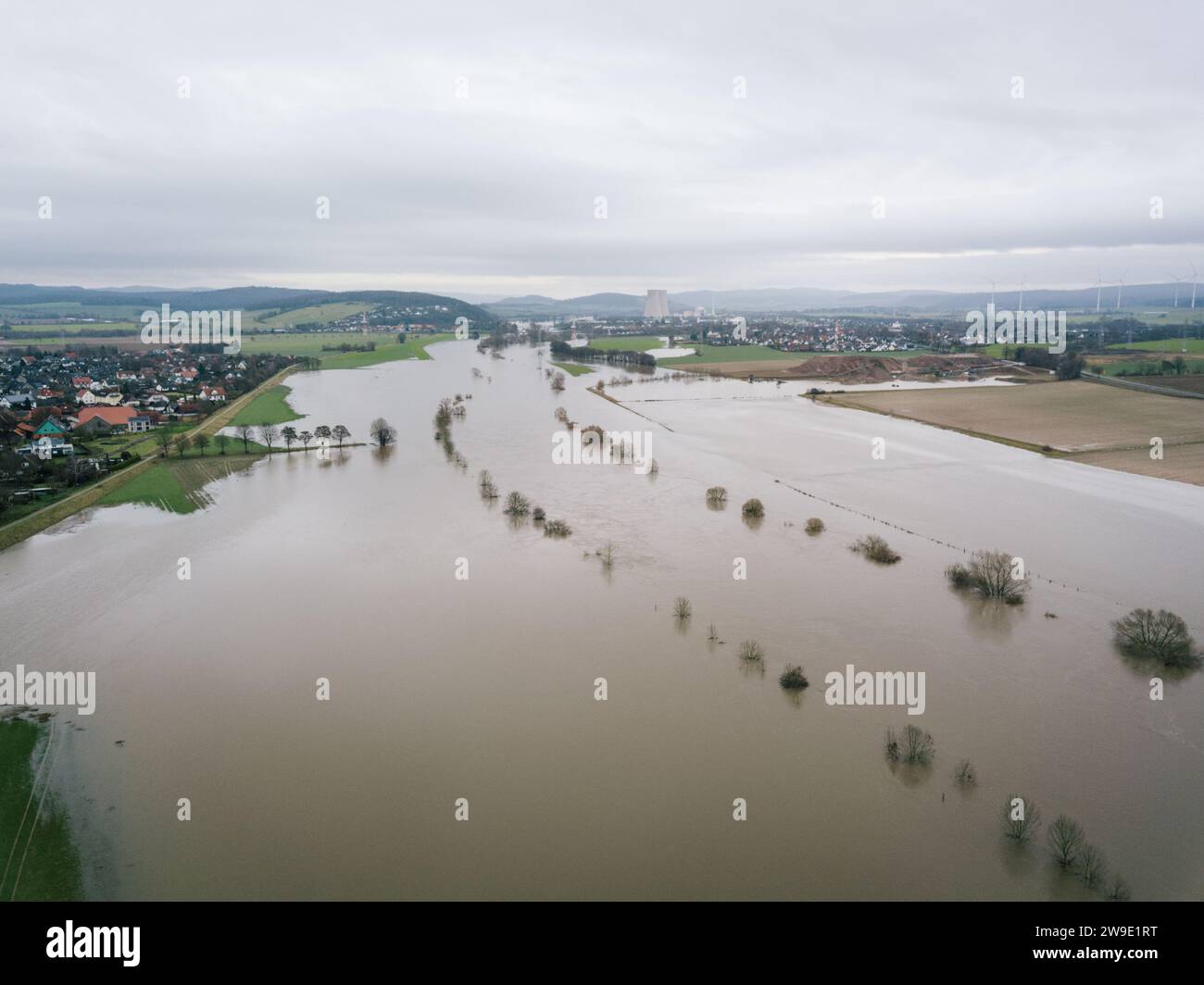 27 dicembre 2023, bassa Sassonia, Tündern: Prati e campi sono allagati dalle alte acque del Weser. La centrale nucleare di Grohnde, chiusa, può essere vista sullo sfondo. Le inondazioni continuano a mantenere la bassa Sassonia sui tenterhook. Mentre il livello dell'acqua sta diminuendo di nuovo in alcuni luoghi, continua a salire altrove. Foto: OLE Spata/dpa Foto Stock