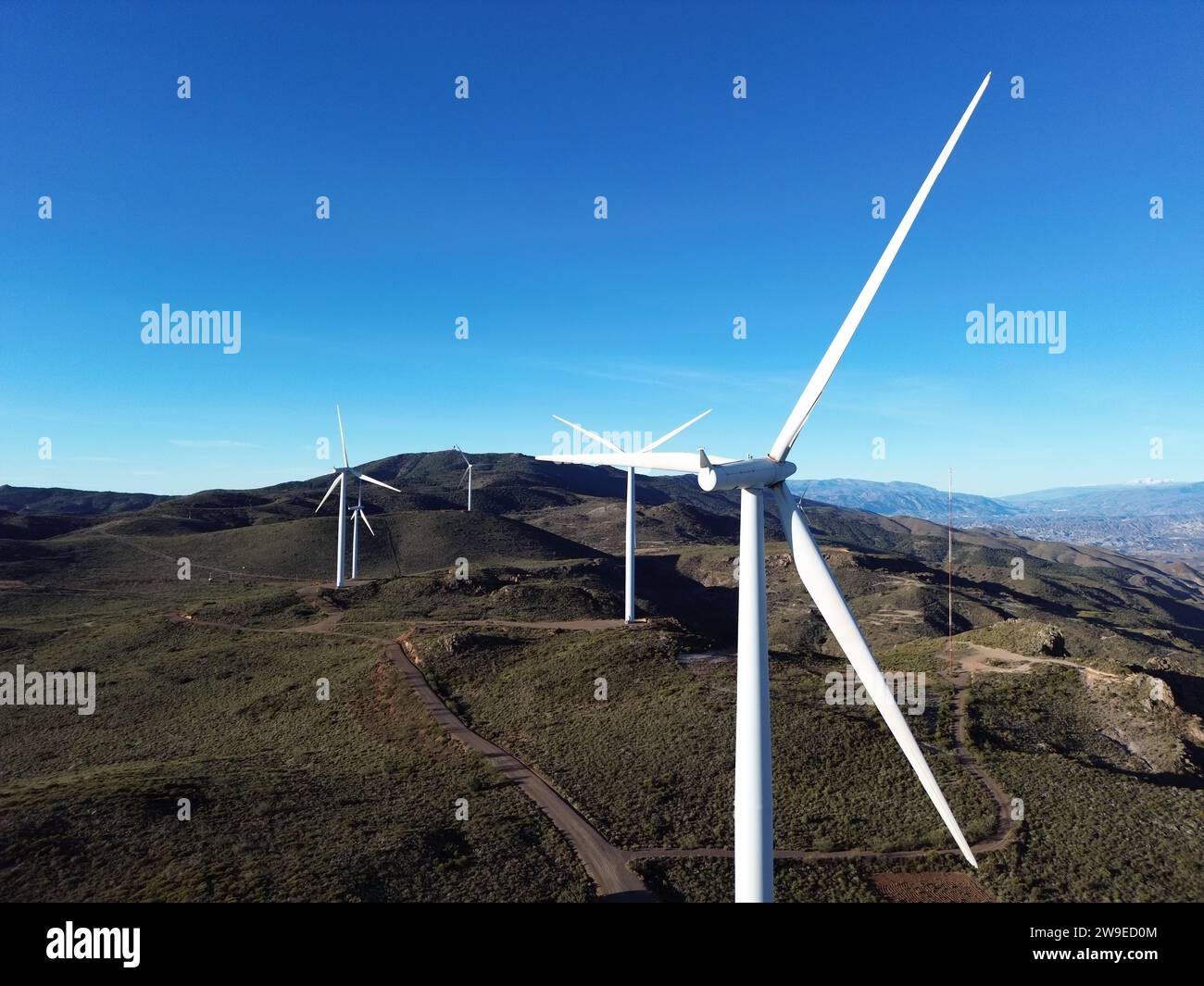 Le turbine eoliche in un paesaggio montuoso sullo sfondo di un cielo blu Foto Stock