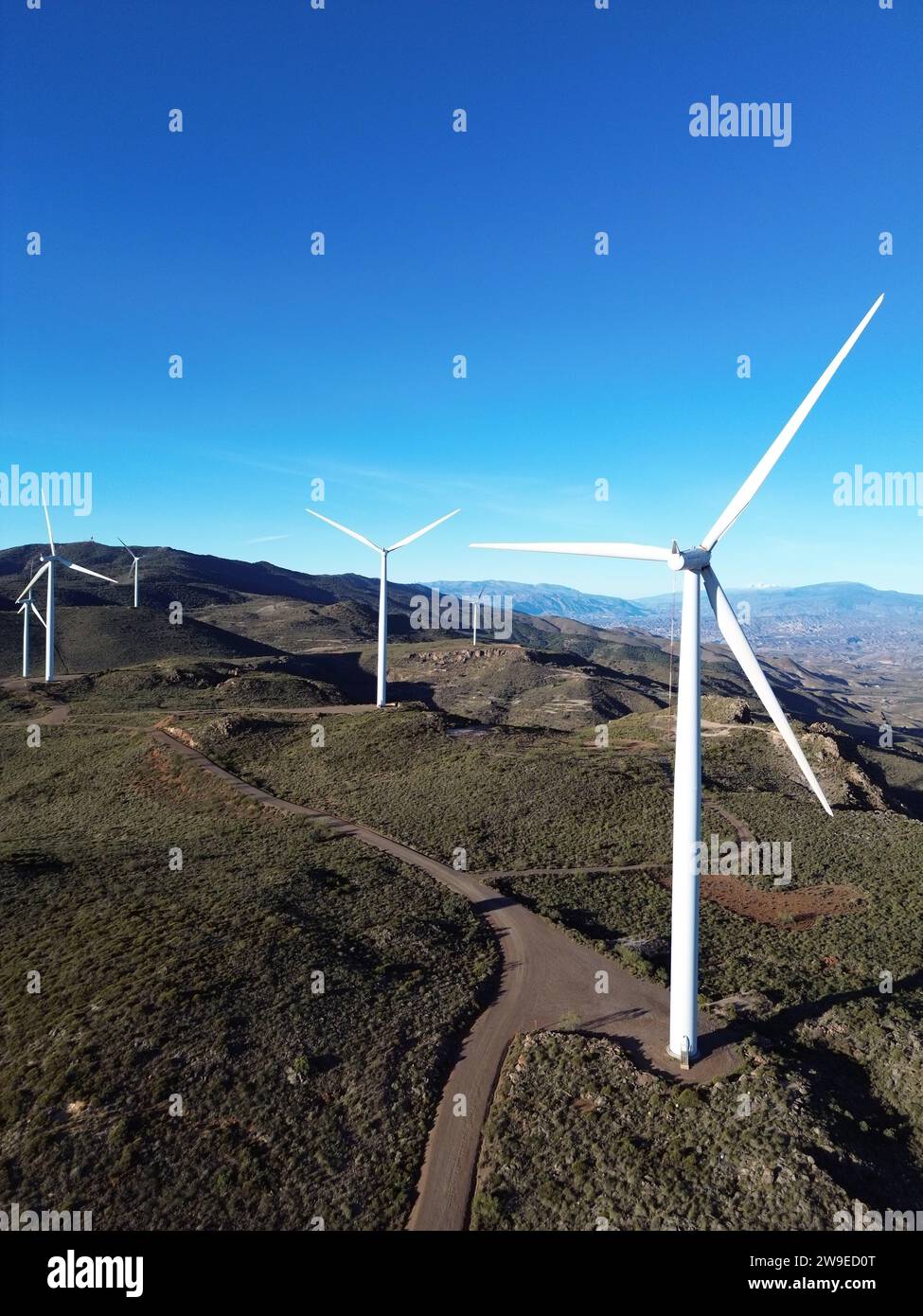 Le turbine eoliche in un paesaggio montuoso sullo sfondo di un cielo blu Foto Stock