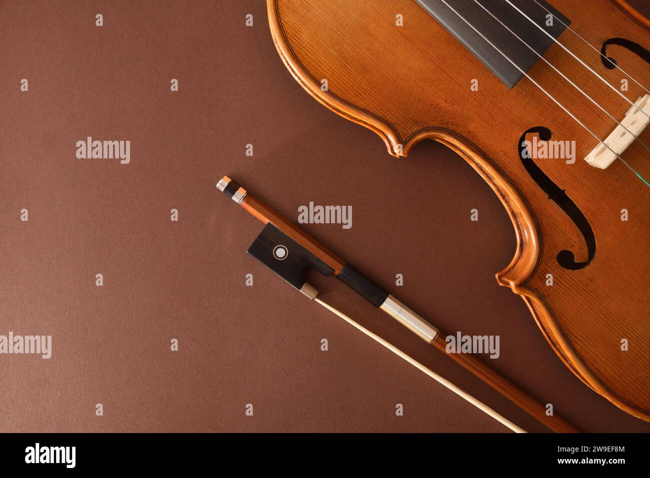 Violino e arco tradizionali disposti diagonalmente su sfondo marrone sfumato isolato. Vista dall'alto. Foto Stock