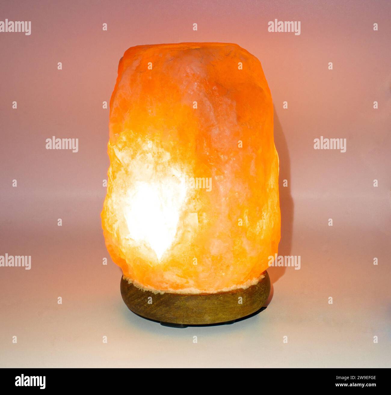 Lampada Himalayana rosa con luce rossa arancione isolata su sfondo chiaro che può migliorare l'umore, migliorare il sonno, alleviare le allergie, ridurre l'ansia e la cle Foto Stock