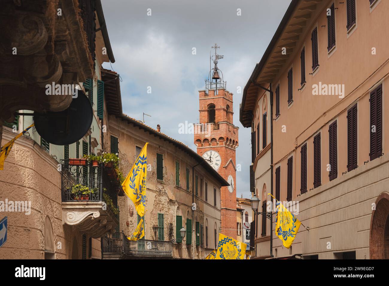 Asciano, Italia - 30 agosto 2023: Torre dell'orologio lungo la strada principale e il centro storico del pittoresco e affascinante borgo toscano di Asciano Foto Stock