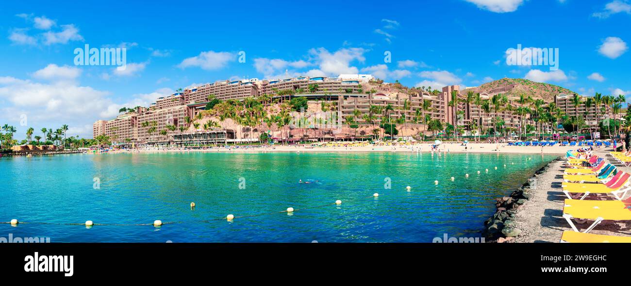 Anfi del Mar Resort, Gran Canaria: Giorno d'estate, vista panoramica delle acque turchesi, spiaggia, architettura del resort e sdraio che costeggiano la riva Foto Stock