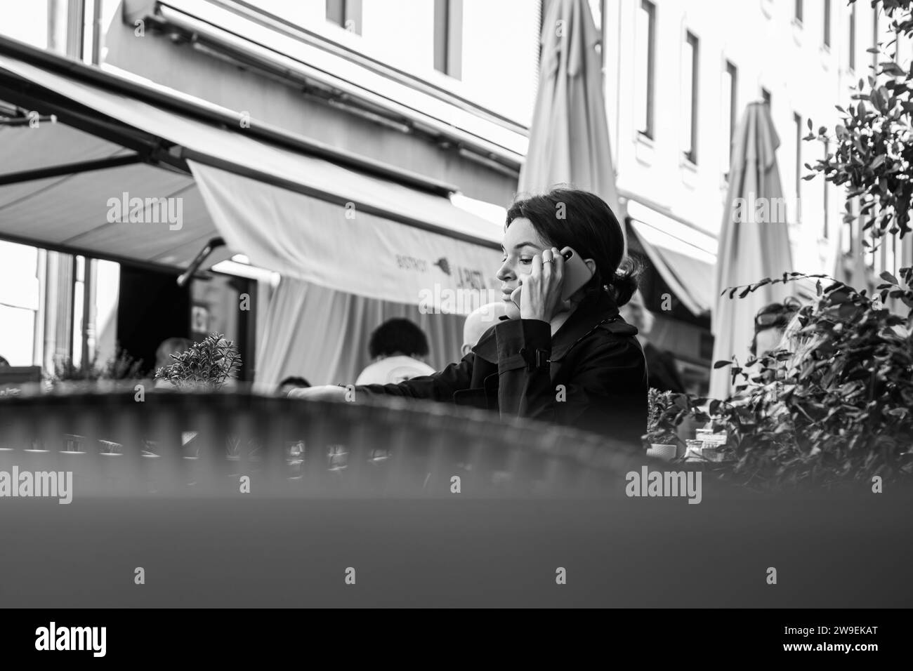 Donna seduta in un caffè all'aperto che parla al telefono, Como, Italia Foto Stock