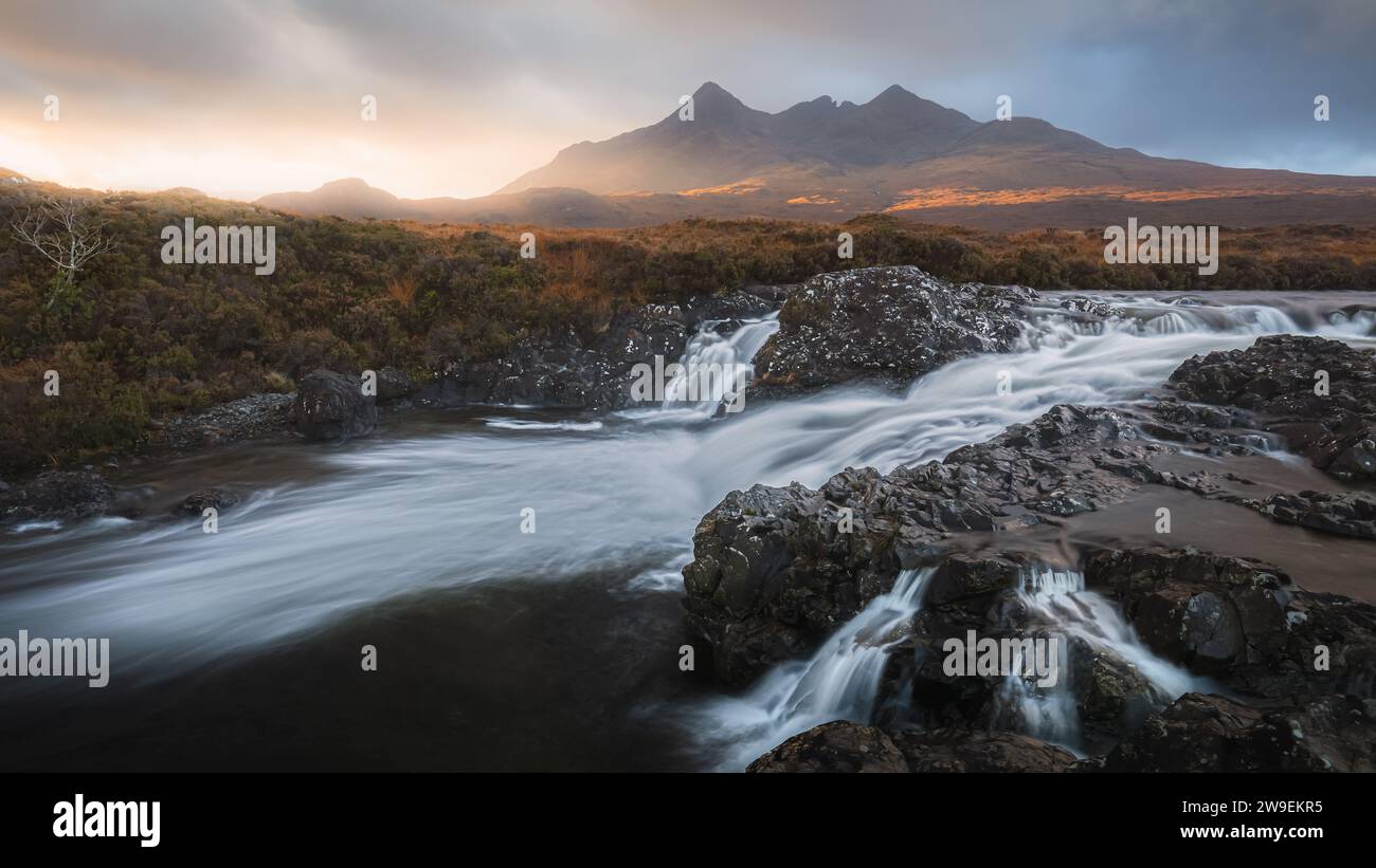Una vista spettacolare del vecchio ponte di Sligachan mentre il fiume scorre sotto e le montagne Cuillin si stagliano sullo sfondo. Foto Stock