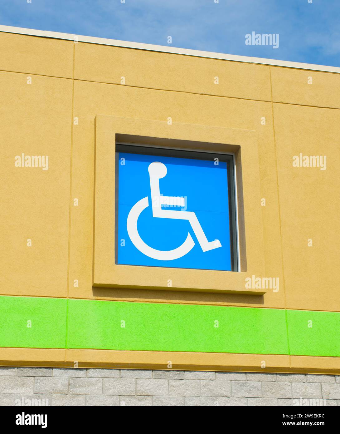Icona di una persona su una sedia a rotelle sulla facciata esterna dell'edificio. Segnaletica blu brillante per la visibilità. Blu Foto Stock