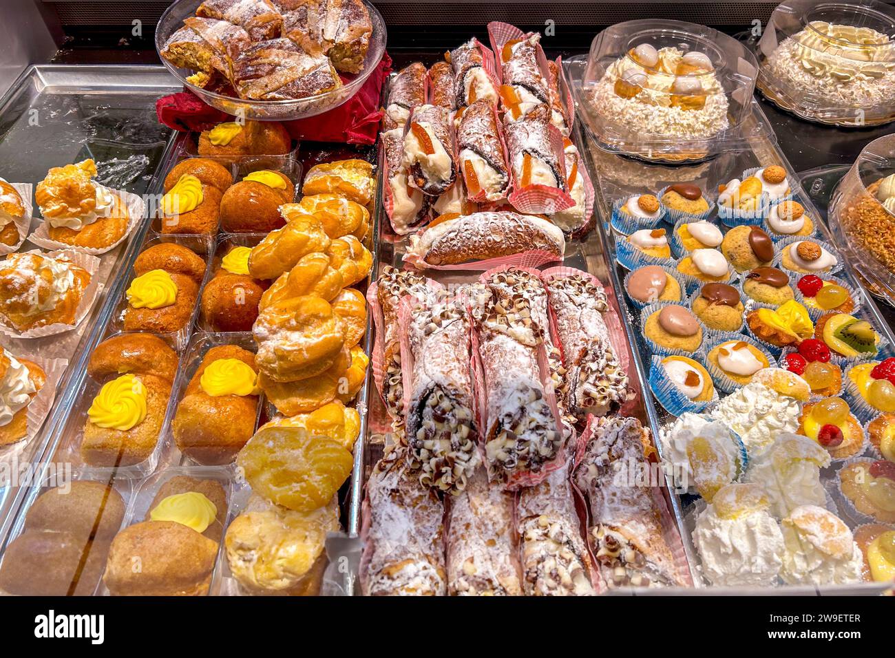 Pasticceria italiana esposta nel bancone della finestra, pasticceria ripiena di panna e cioccolato, cannoli siciliani e torte alla panna Foto Stock