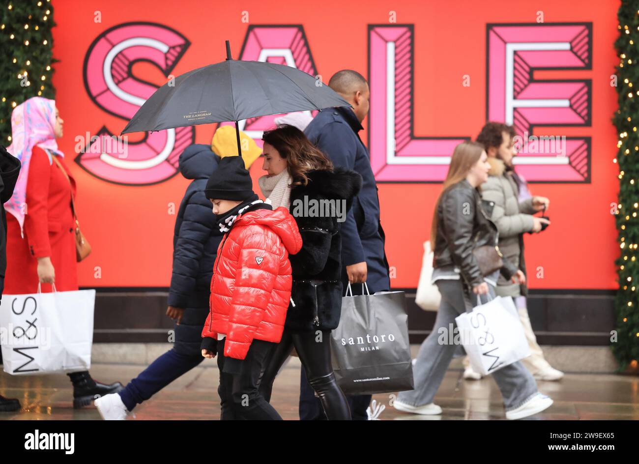 Londra, Regno Unito, 27 dicembre 2023. Gli acquirenti si sono vantati dei venti ventosi e delle forti piogge di Storm Gerrit su Oxford Street, mentre le vendite del giorno di Santo Stefano continuavano. Nonostante la tempesta, le temperature rimangono instagionalmente miti. Credito : Monica Wells/Alamy Live News Foto Stock