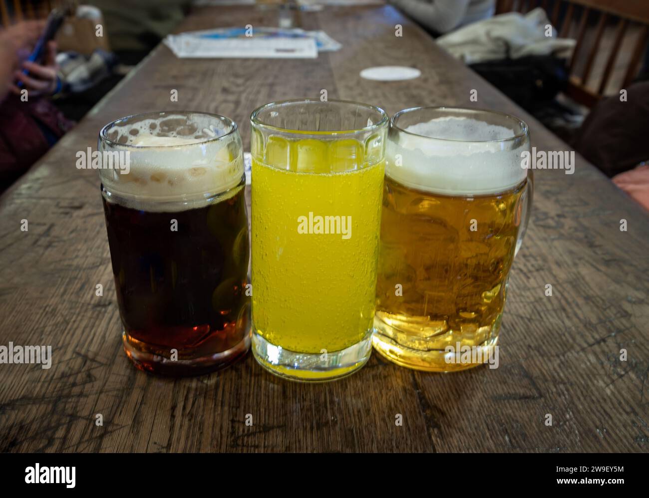 Tre bicchieri di diversi tipi di birra fredda e gustosa sono in fila su un tavolo di legno in un ristorante. Tavolo per la compagnia degli amici, spazio per testo, Sele Foto Stock