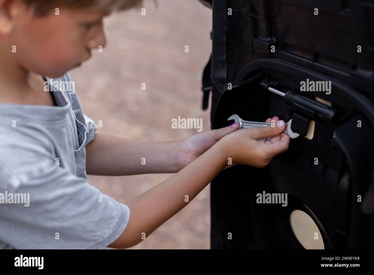 Interessato al futuro meccanico, ragazzo, esplora la chiave per riparare il suo scooter, la passione per la tecnologia. Foto Stock