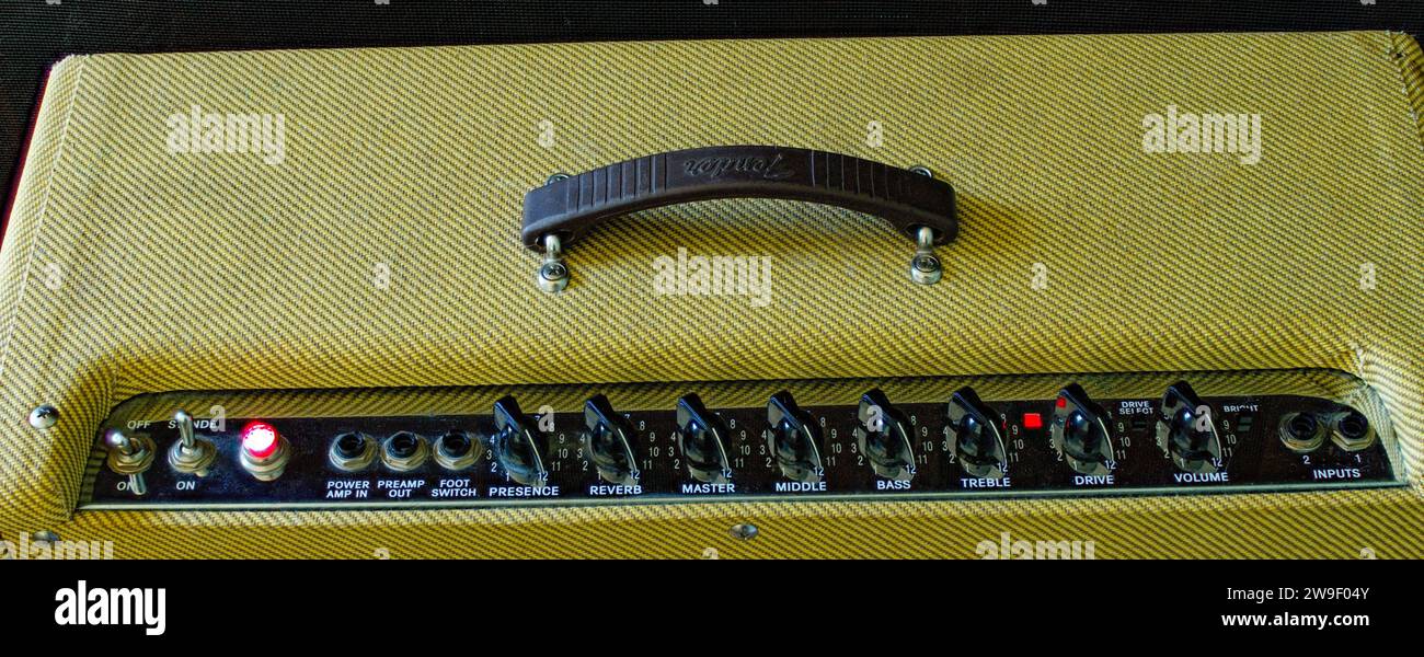 Vecchio amplificatore a tubo per chitarra in stile retrò o amplificatore con tweed giallo isolato su sfondo scuro. Pannello di controllo volume , alti, bassi, pulsante tono Foto Stock