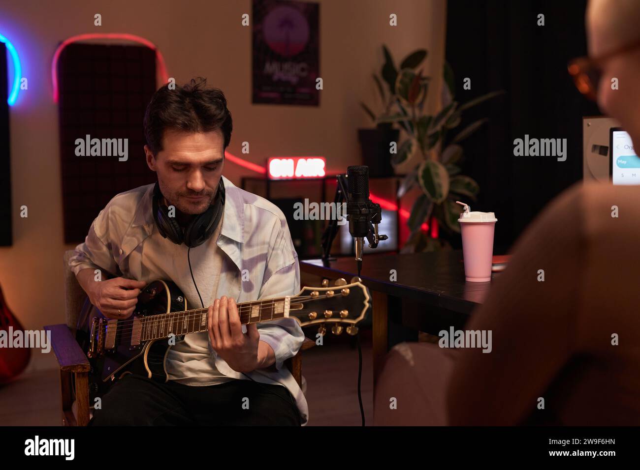 Musicista concentrato che suona la chitarra durante il podcast Foto Stock