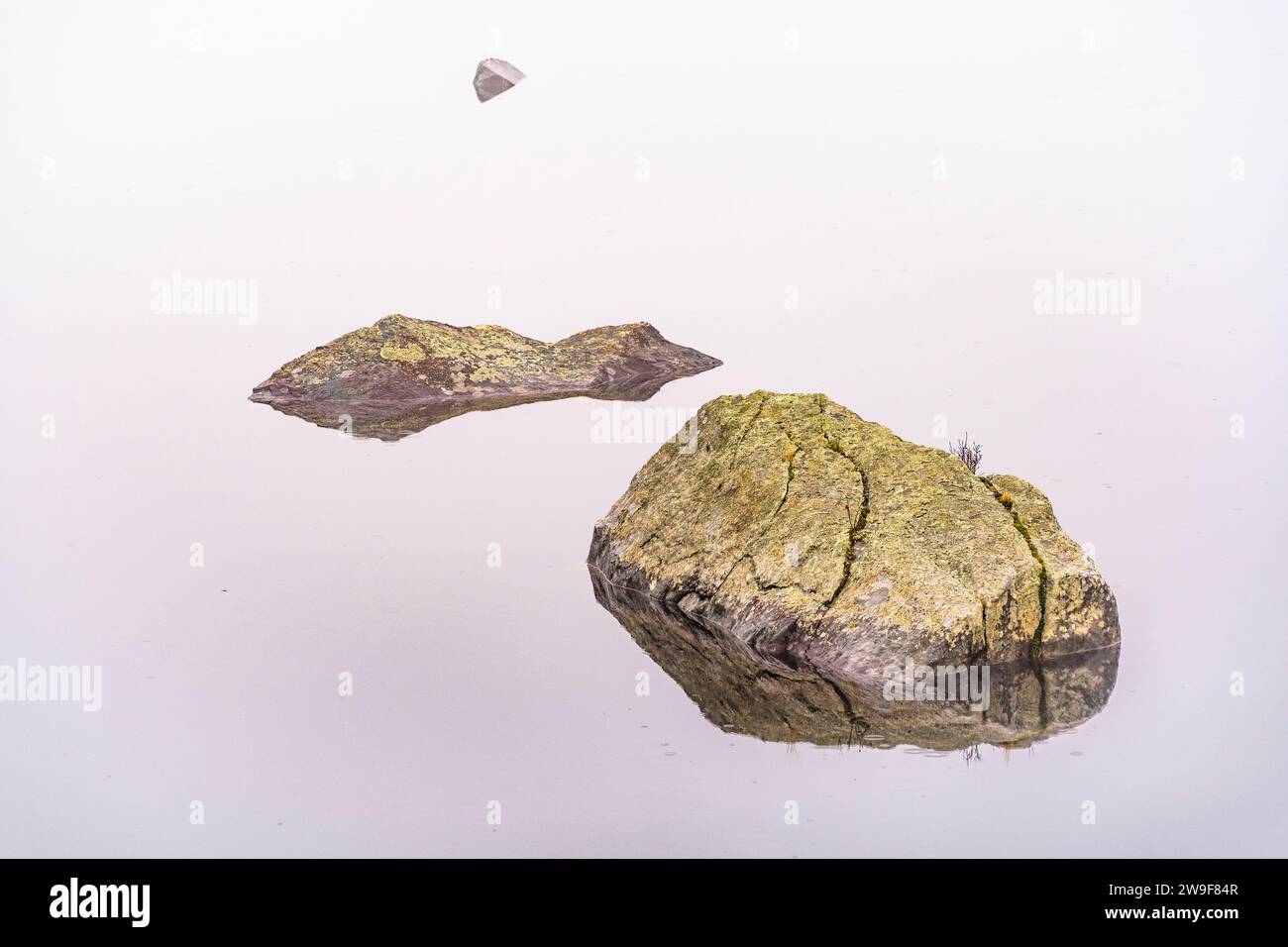 Rocce che si innalzano da un lago calmo. Foto Stock