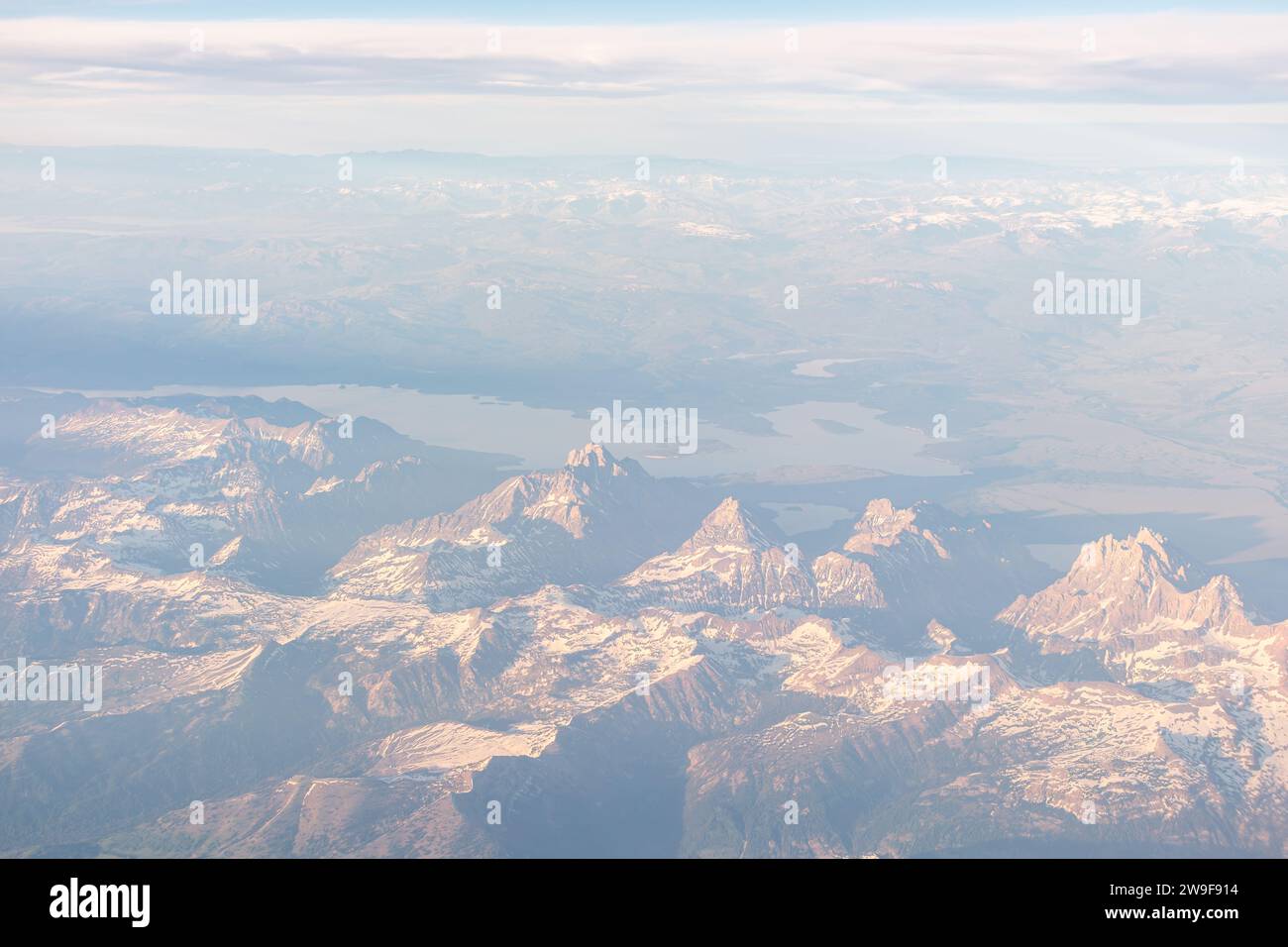 Grand Tetons si staglia maestosamente sotto, visto dal finestrino di un aereo passeggeri. Foto Stock