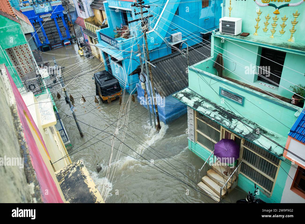 Una figura solitaria si erge tra le acque che si innalzano di una strada della città allagata Foto Stock